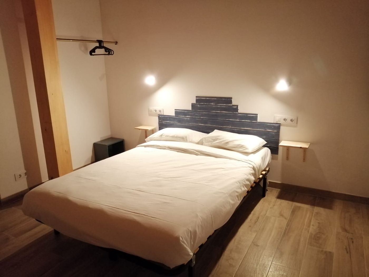 Habitación Peru en Lastoetxe, con cabecero azul marino y mesillas de pared