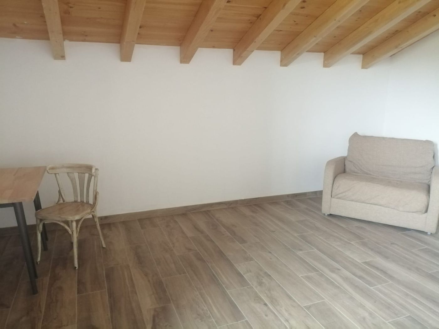 Zona común de Lastoetxe con vigas de madera vista y acceso al balcón exterior